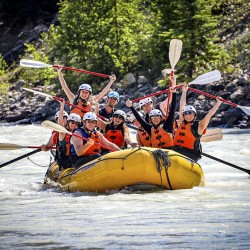 family with paddle in the air and big smiles as they raft kicking horse river