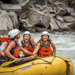 guests smiling and waving in raft on kicking horse