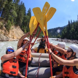 Rafters smiling and giving a paddle high 5 on the Kicking Horse River