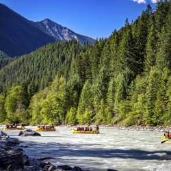rafts going down kicking horse river surrounded by trees and mountains