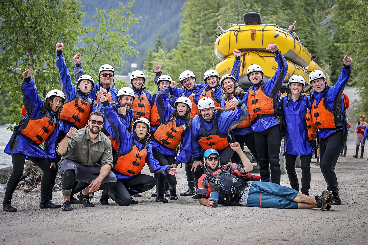 A group smiling and giving thumbs up after rafting the Kicking Horse River in the rain
