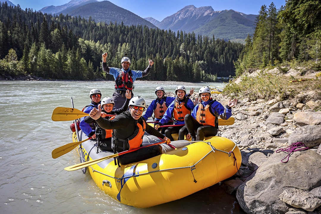 family smiling and waving before starting to raft kicking horse river